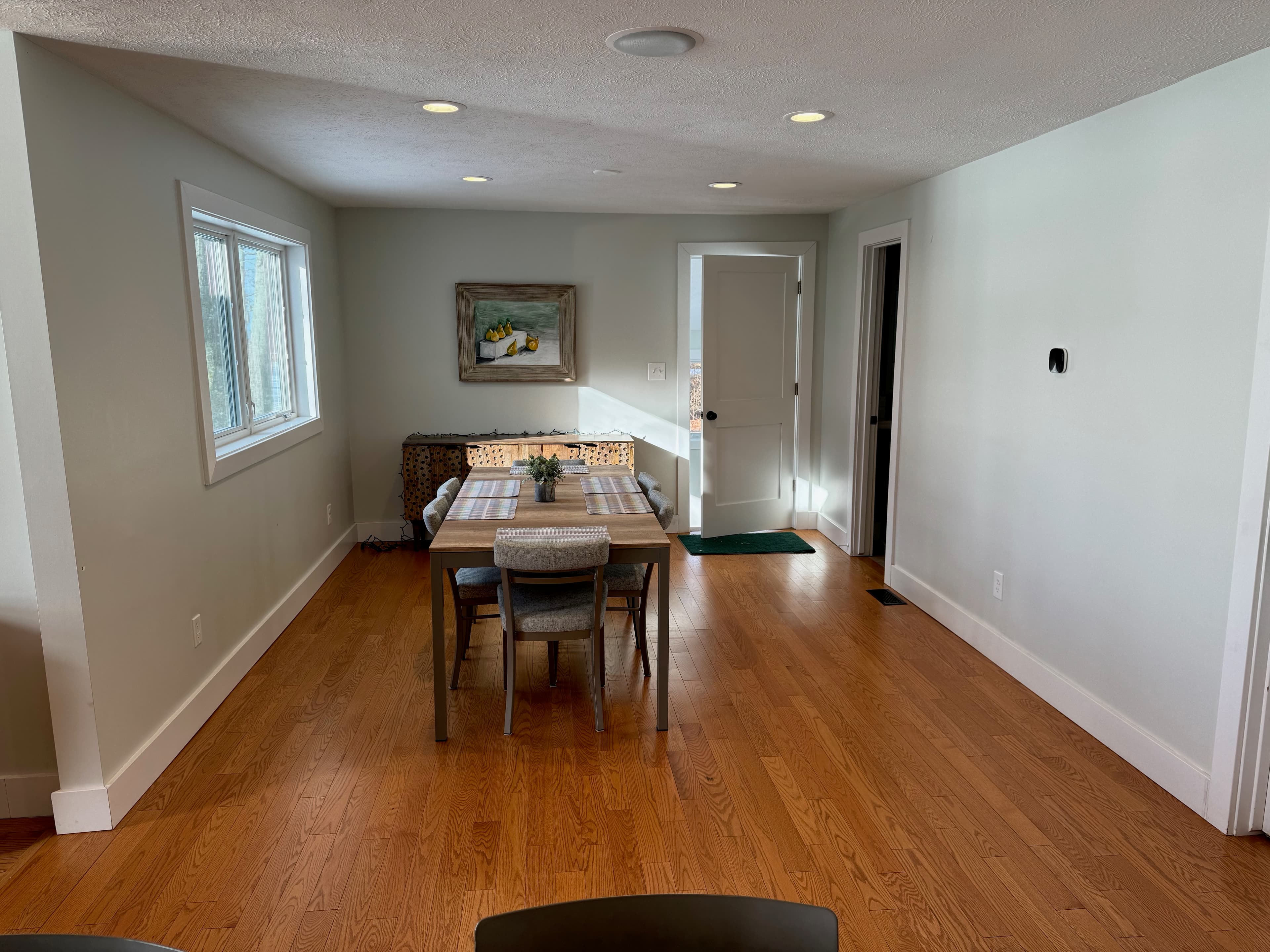 Dining area with table for six, natural light, and view into hallway