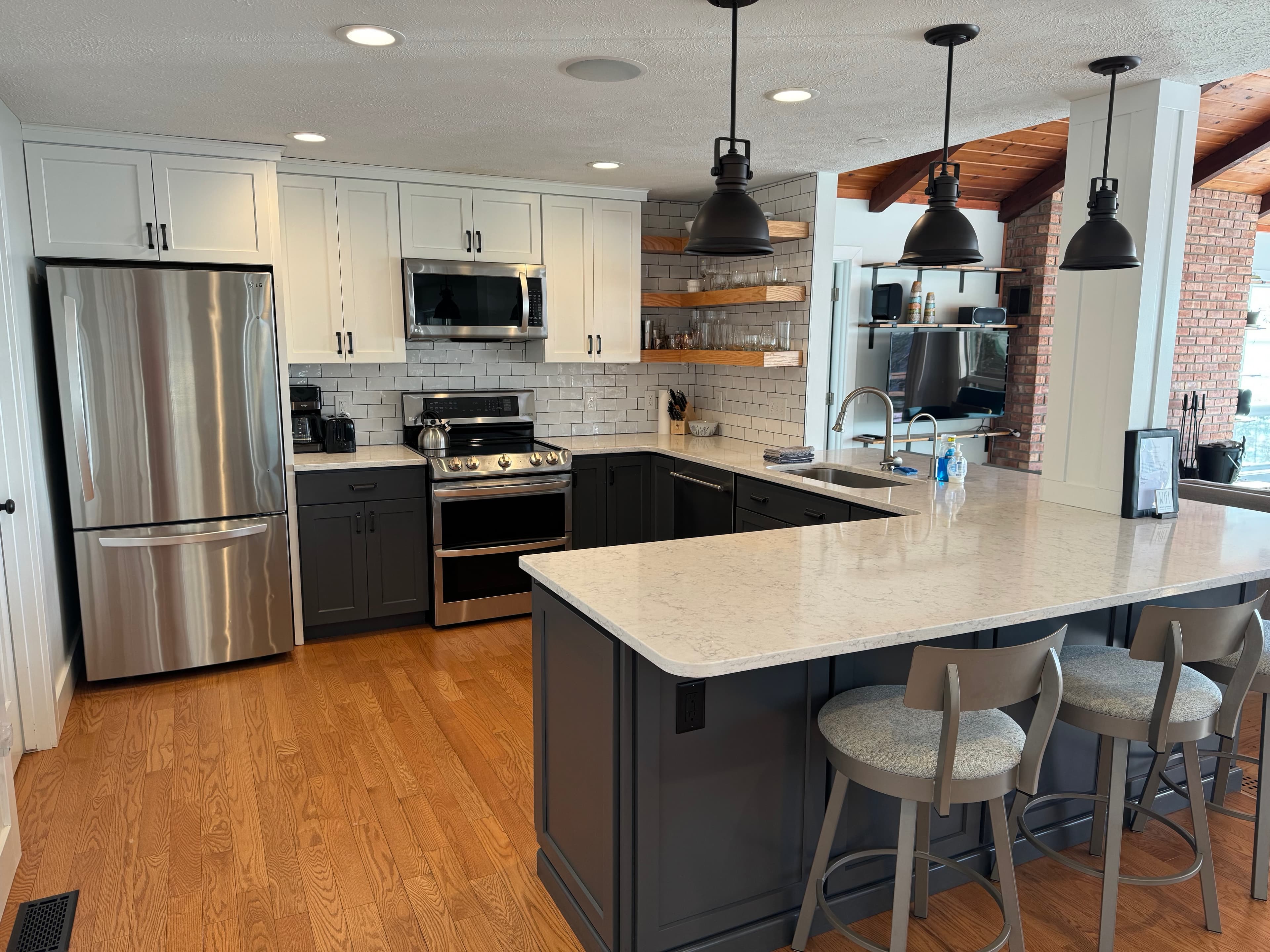 Chef's kitchen with gas range, quartz island, subway tile, and floating wood shelves