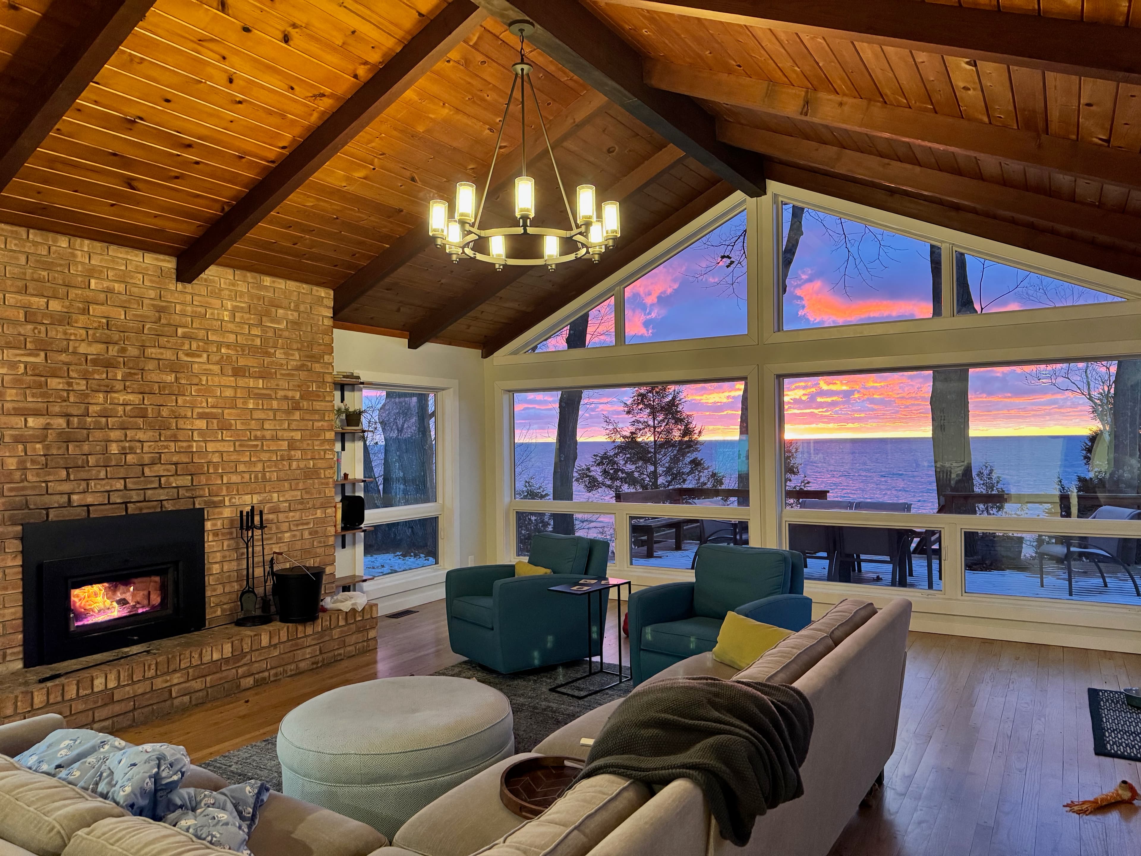 Cozy evening in living room with wood stove fire burning, dramatic pink sunset through windows