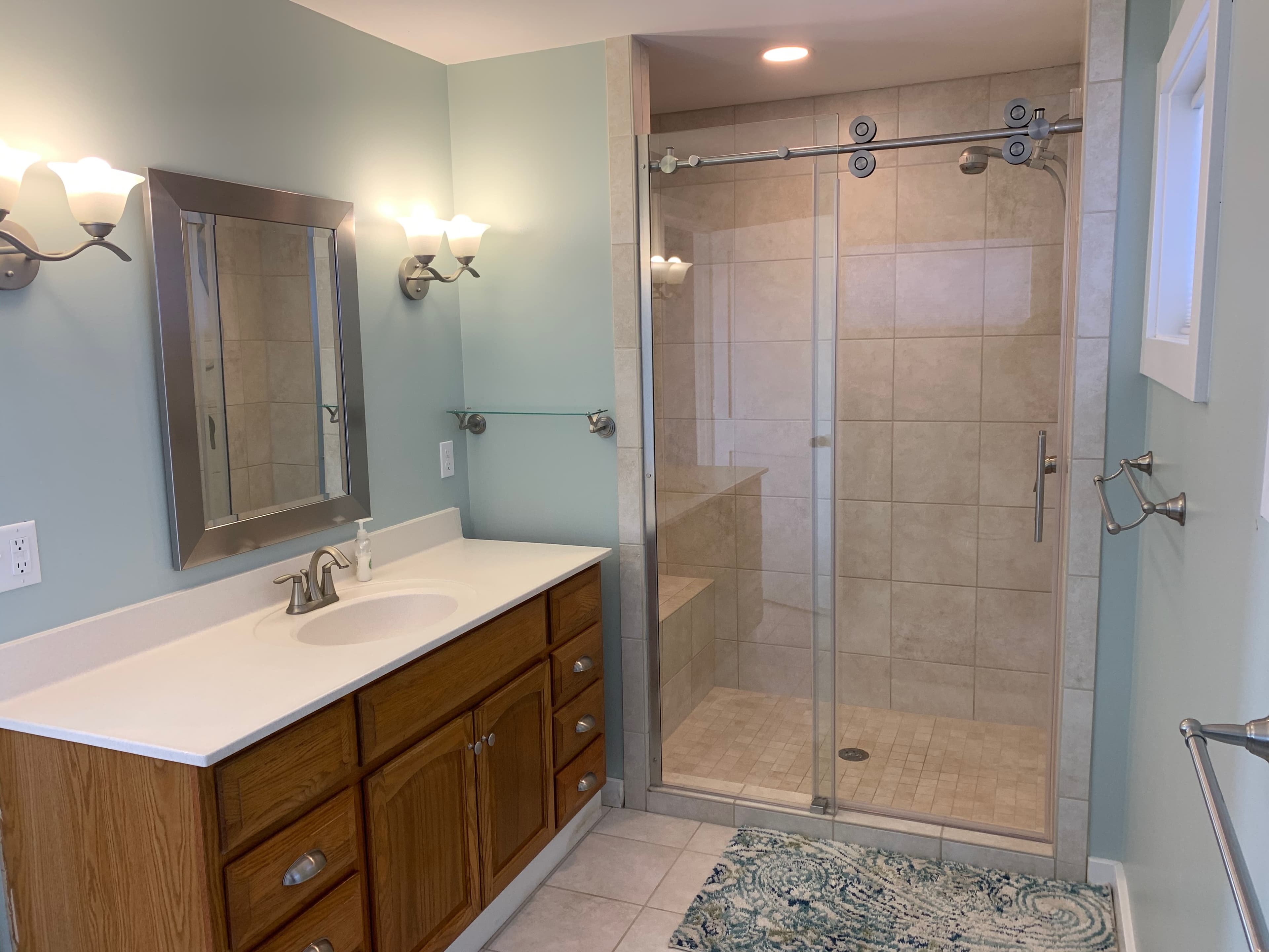 Master bathroom with glass walk-in shower, oak vanity, and modern fixtures