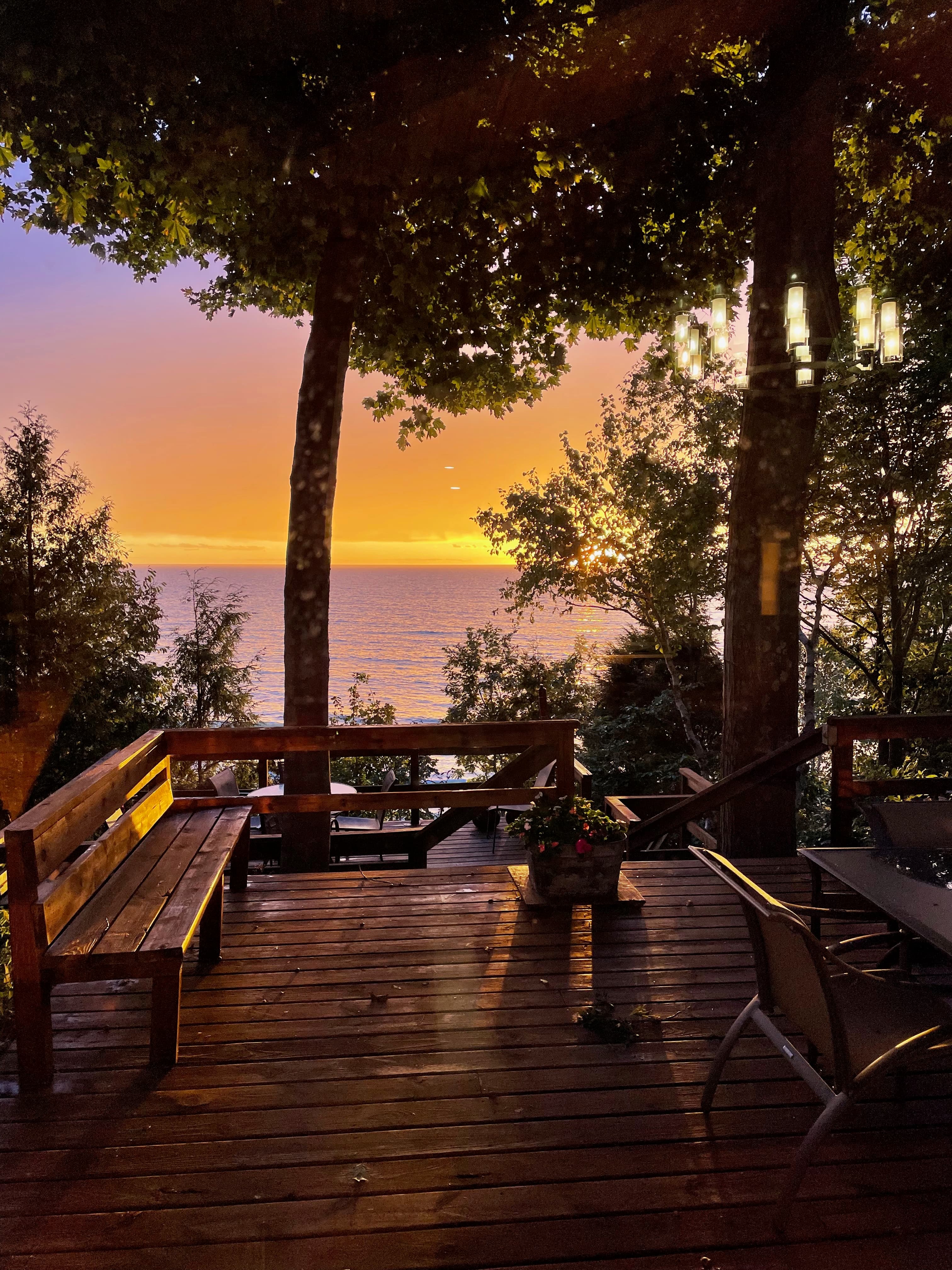 Wooden deck at golden hour with bistro seating overlooking Lake Michigan sunset