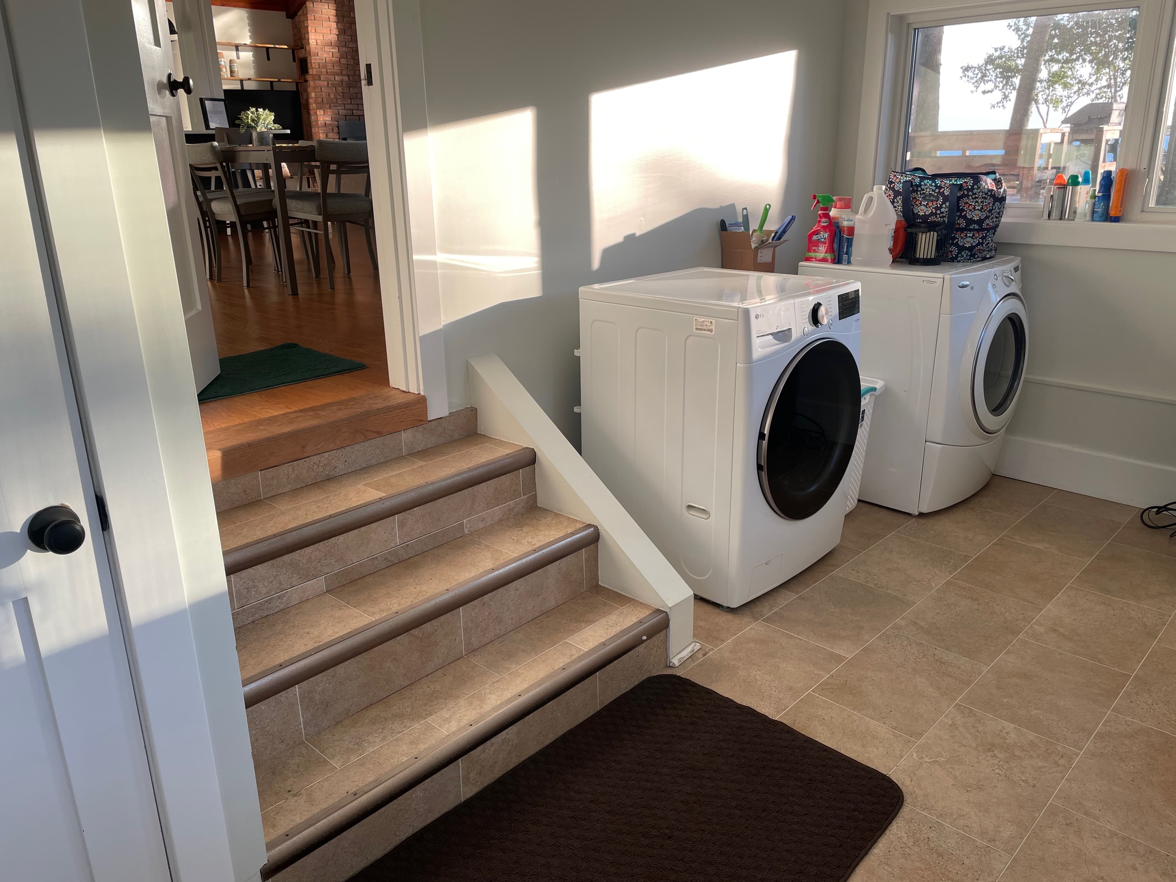 Laundry room with front-load washer and dryer, steps leading to dining area